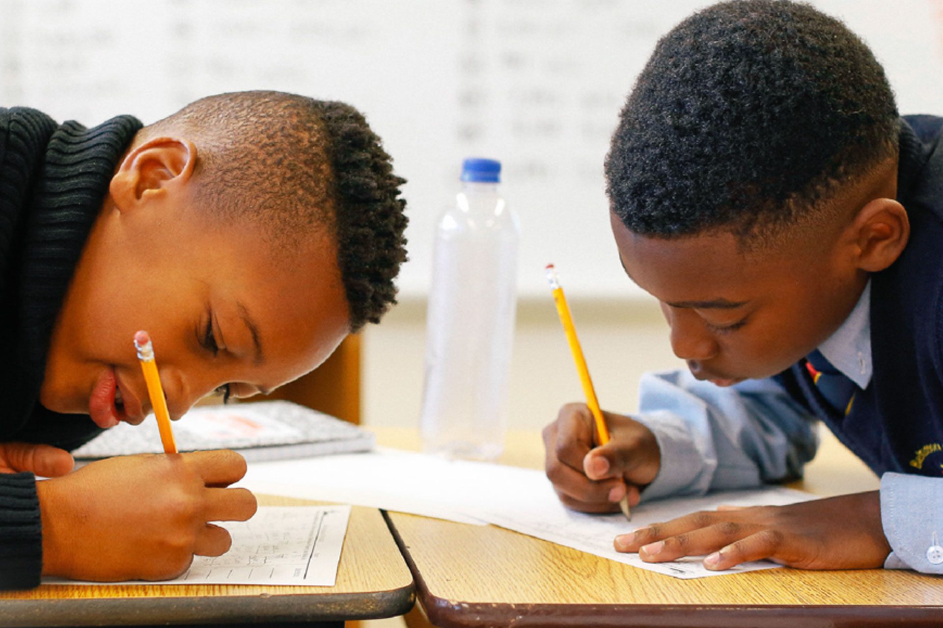 Two boys writing on the paper